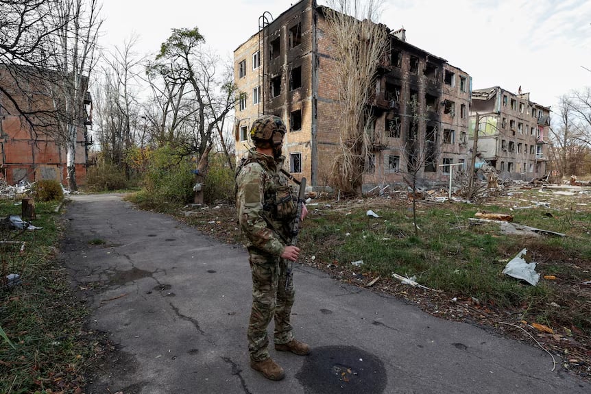 Ukranian soldier in front of bombed building